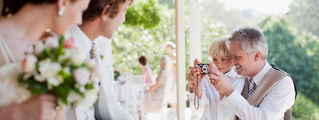 Father and son taking picture of bride and groom.