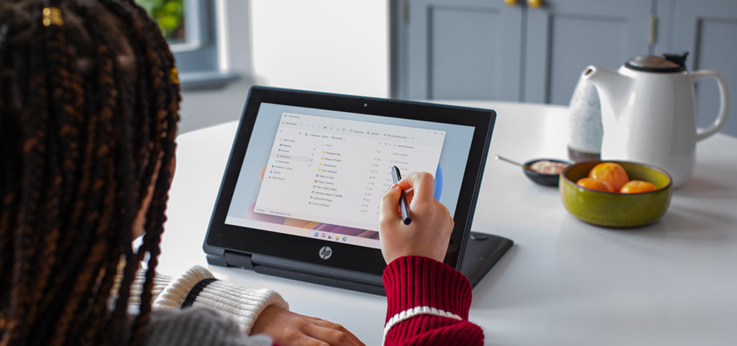 Someone using a stylus on a laptop to select a file.