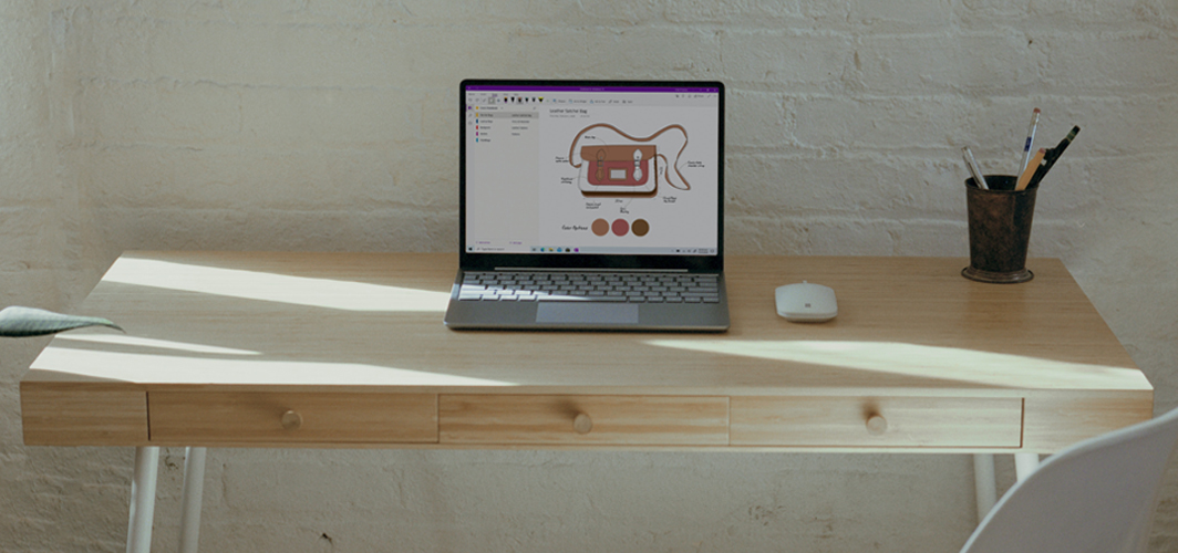A laptop sitting on a minimalist desk with a design for a purse on the screen.