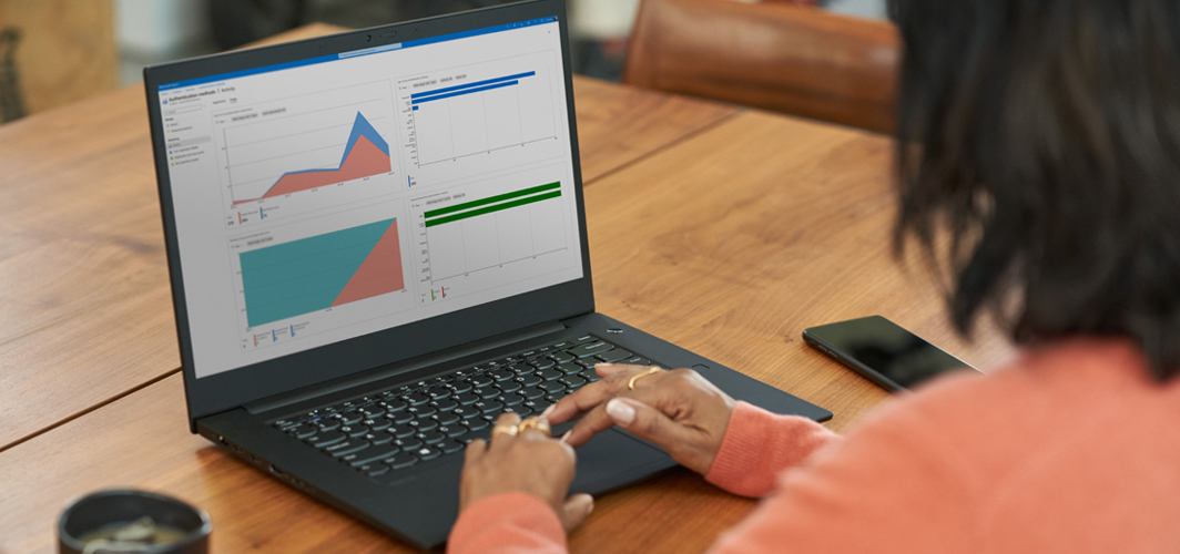 A person using excel to create graphs on a laptop at a wooden table.