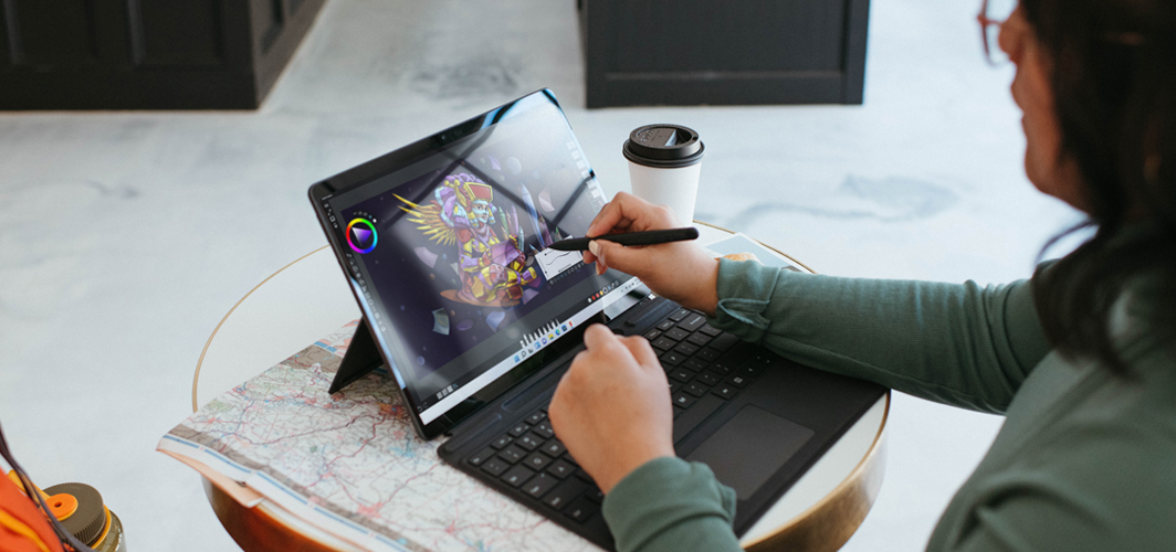 A top down view of someone using a stylus on a tablet computer to create a piece of art.