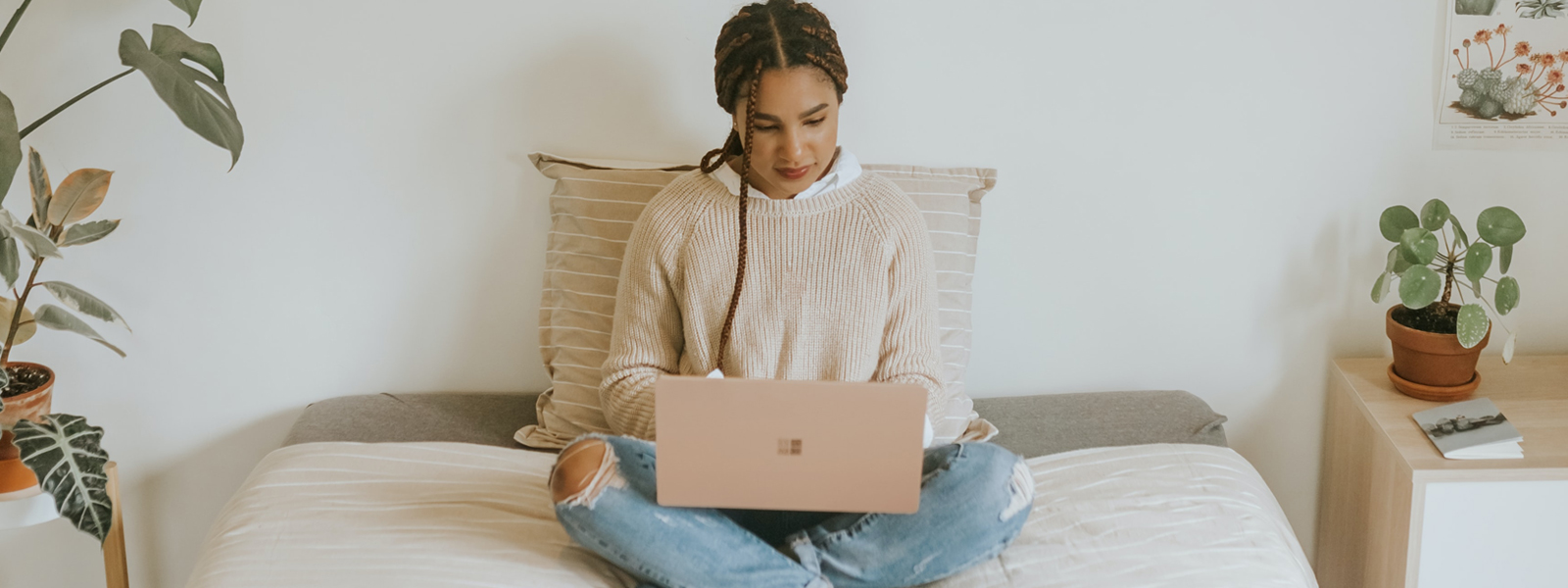 A young woman sitting in bed using her laptop.