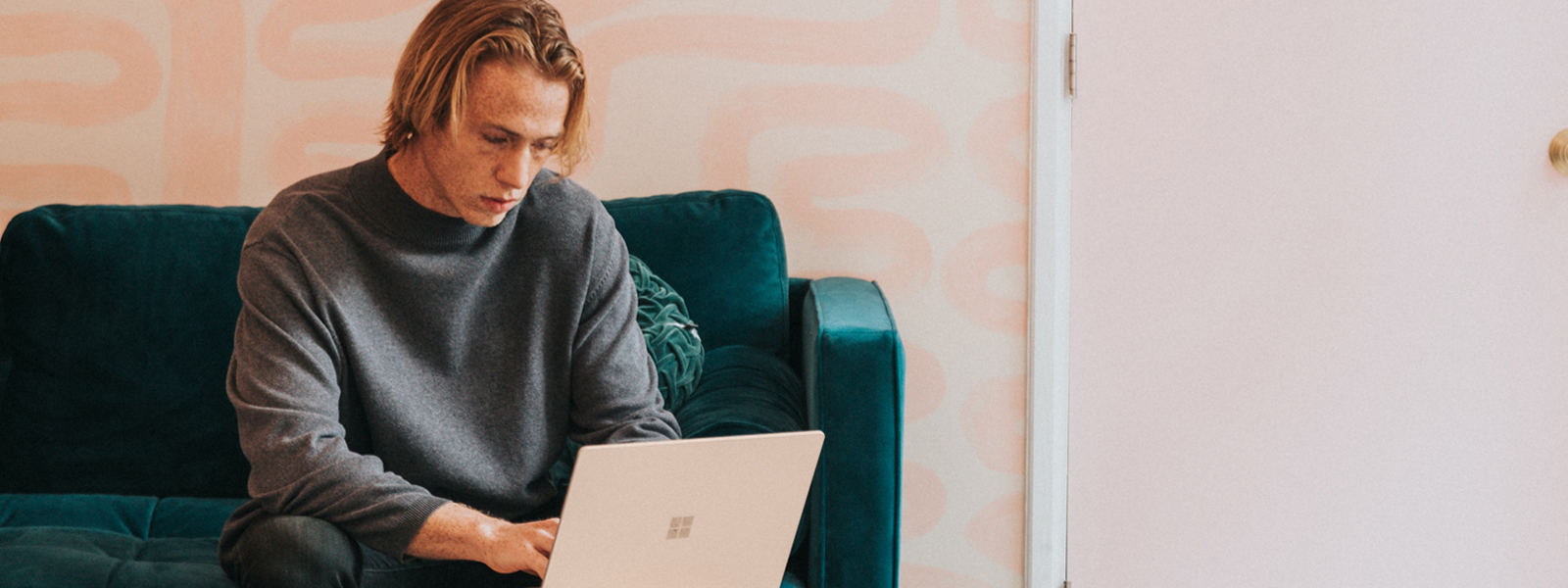 A college student studying with their laptop on a couch.