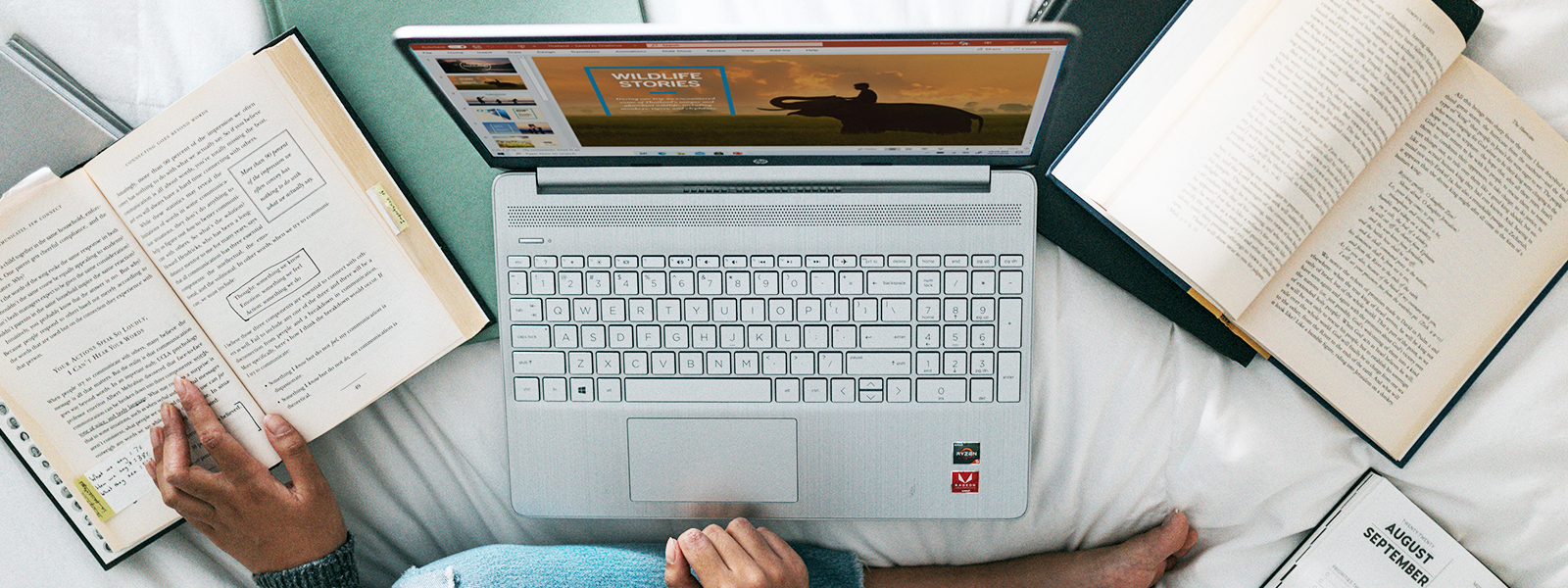 A top down view of someone studying with a laptop and a book with notes and highlights.