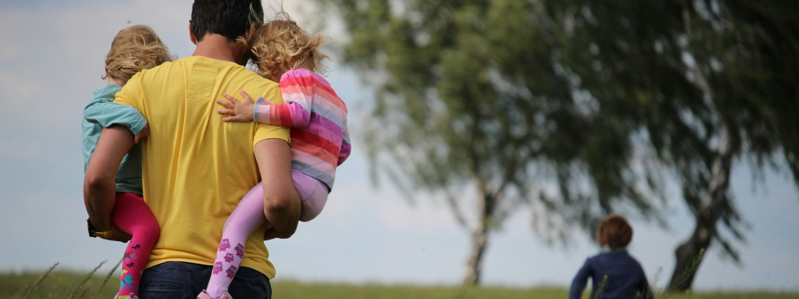 Man carrying his children through a field