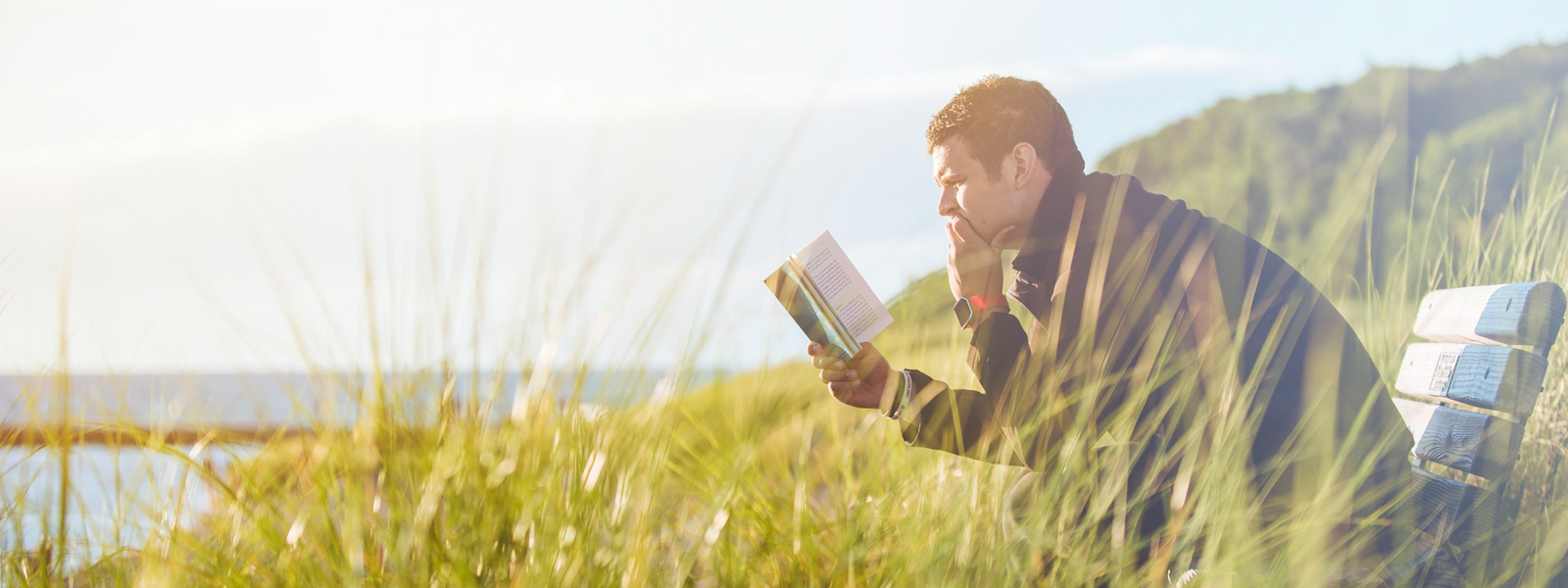 Man sitting on a bench reading a book