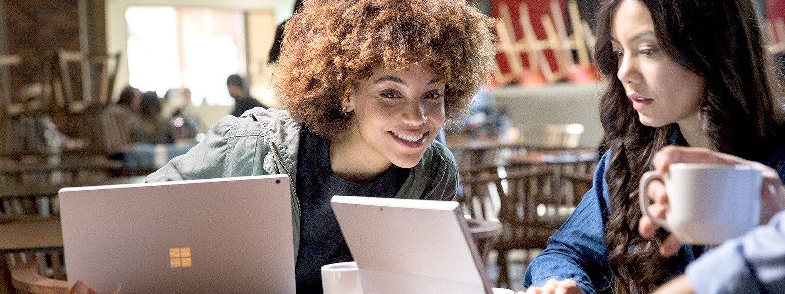 two girls looking at their laptop and smiling.