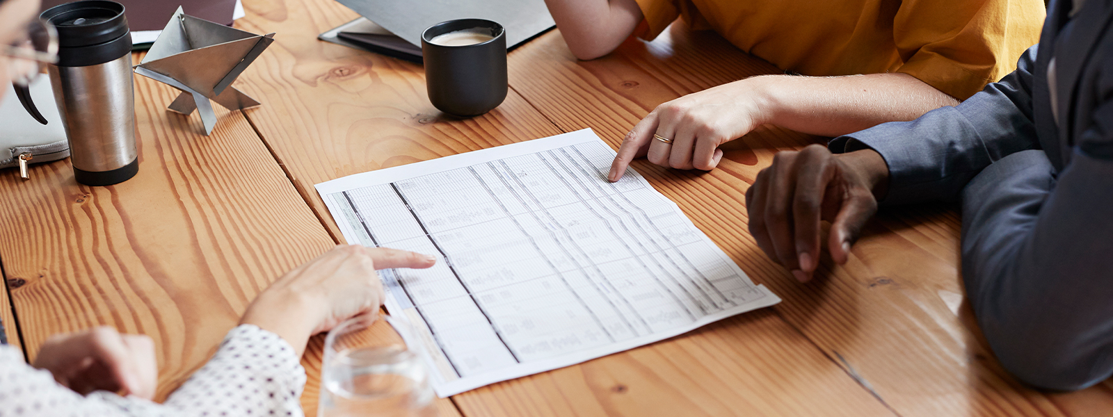 Business professionals discussing a blueprint at conference table in an office.