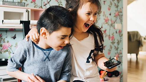 two kids laughing while using a phone