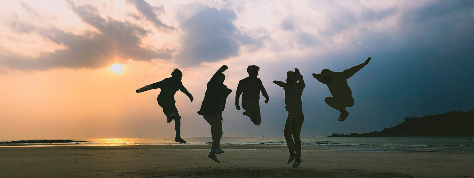 Friends jumping at the beach at sunset
