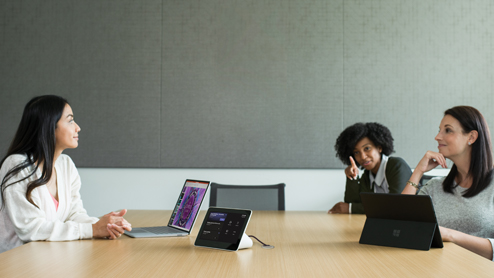 Three females in a medium conference room featuring an Poly Teams Meeting Rooms touch display with the Teams Meeting pre-join screen in view.