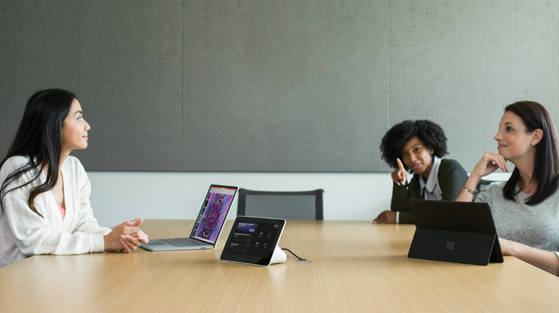 Three females in a medium conference room featuring an Poly Teams Meeting Rooms touch display with the Teams Meeting pre-join screen in view.